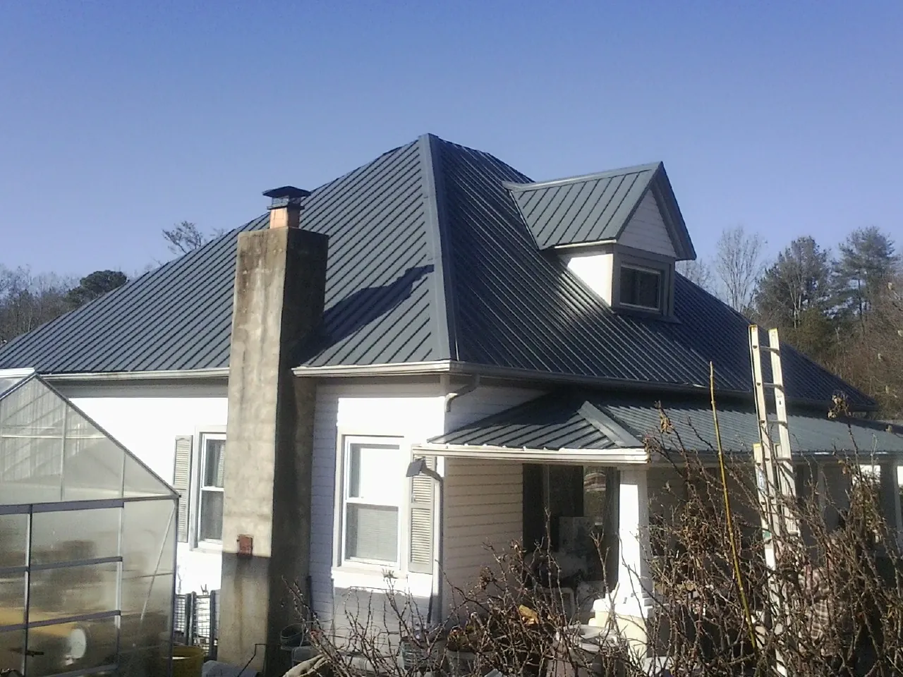 Dark blue standing seam metal roof on a white farmhouse with dormer — Slate & Tile Roof Repair by Roofing Brothers in Dammeron Valley