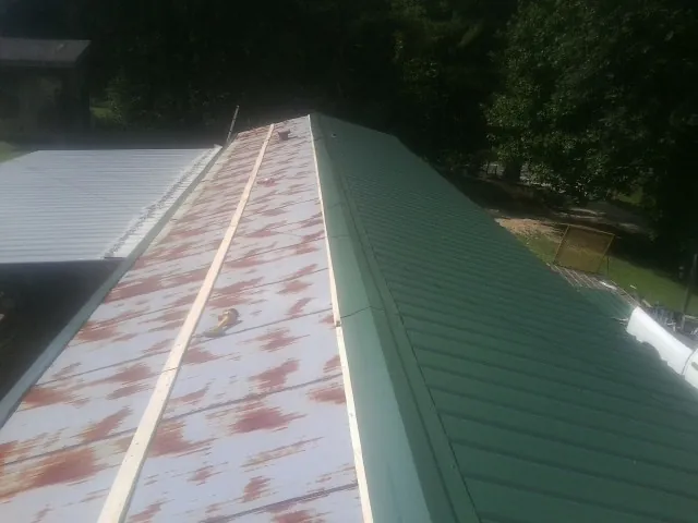 Old rusted panels beside newly installed green metal roofing — Wind Damage Roof Repair by Roofing Brothers in Dammeron Valley