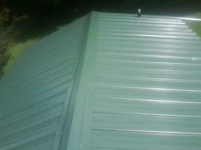 New green metal panels meeting at the ridge of a roof — Flat Roof Repair work by our crew in Dammeron Valley