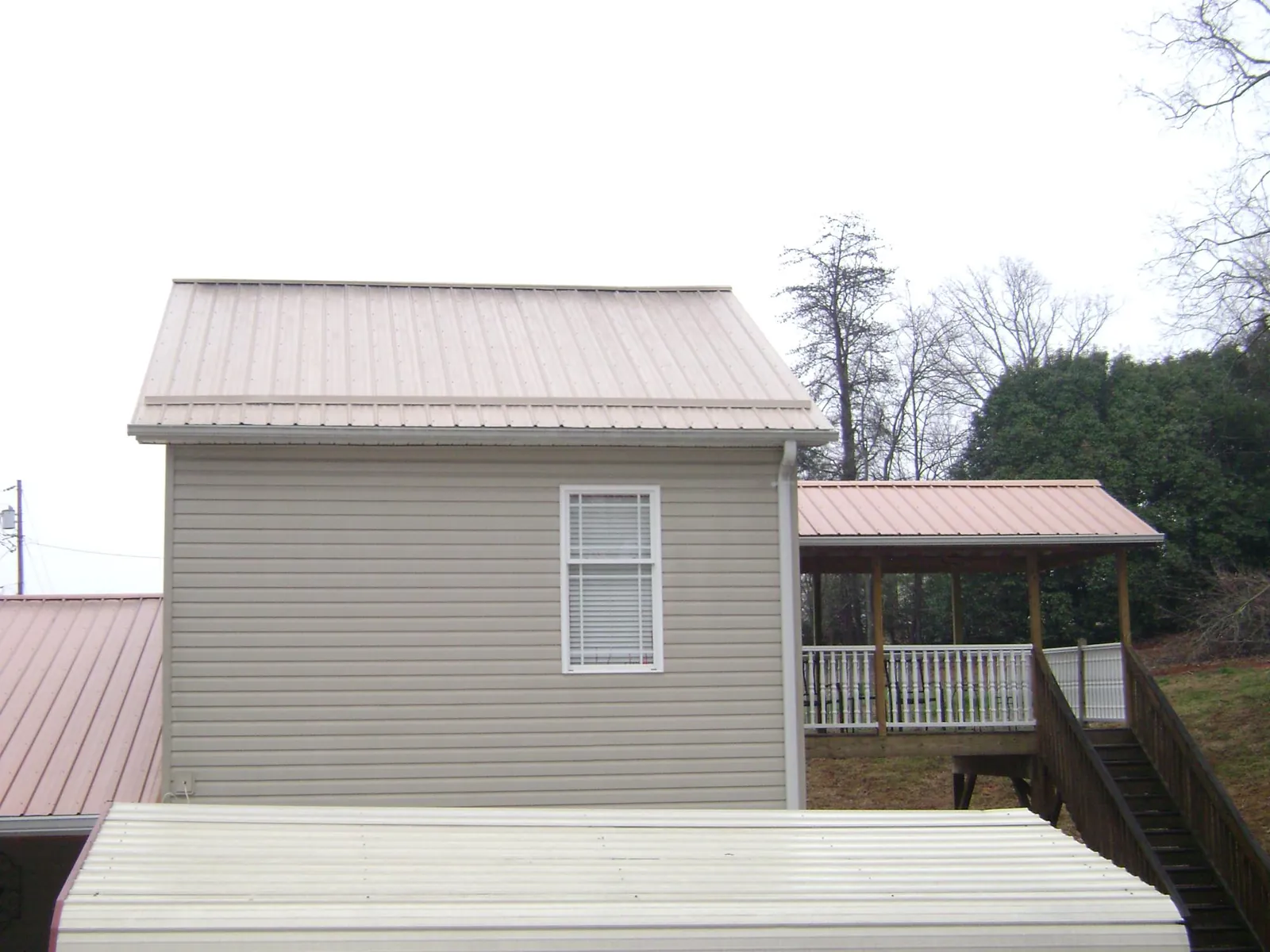 Tan metal roofs on a two story addition and attached porch, from a Roof Replacement job in Dammeron Valley