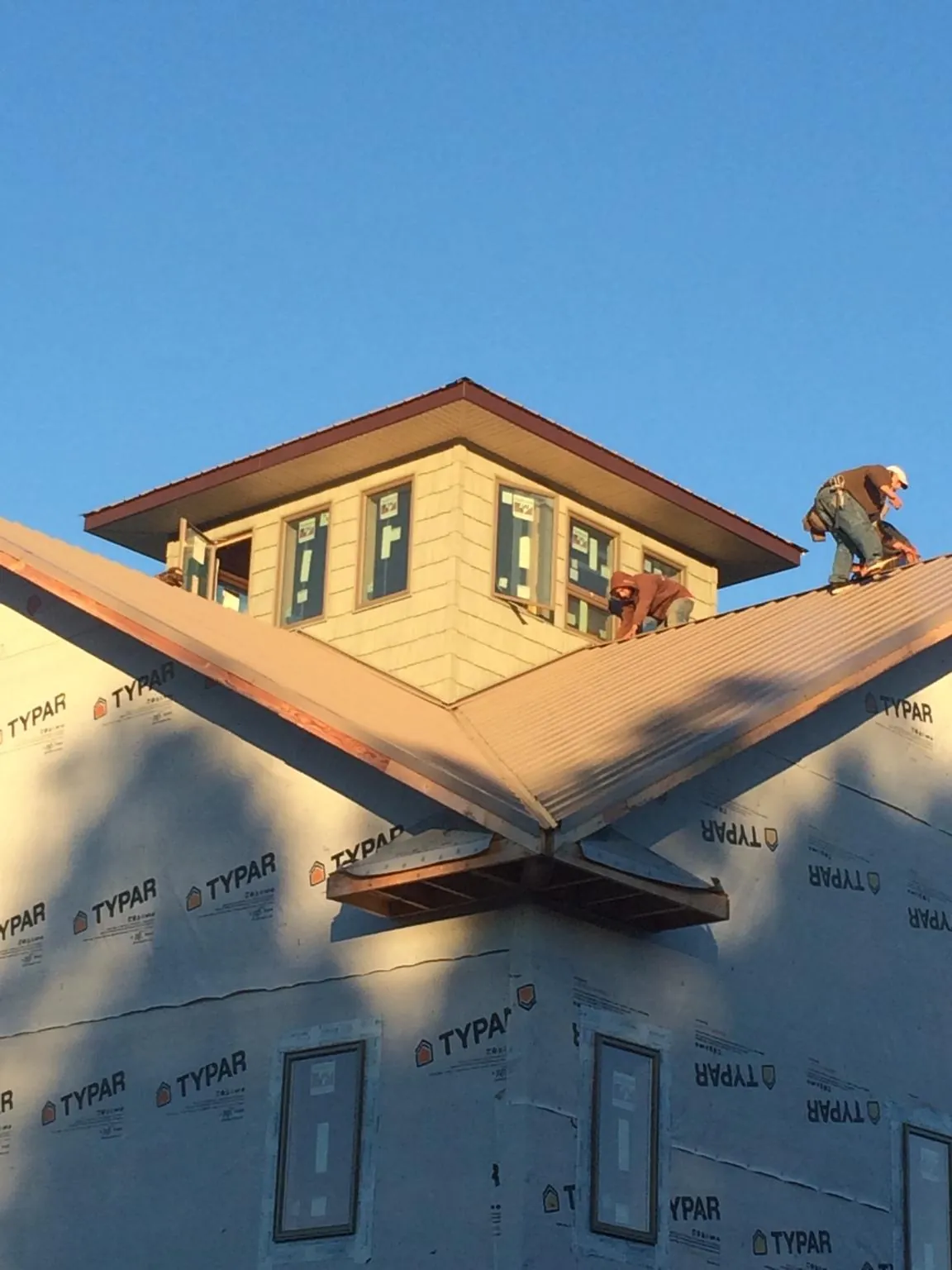 Roofers working around a rooftop cupola on a new metal roof at sunset — Roof Waterproofing in Dammeron Valley by Roofing Brothers